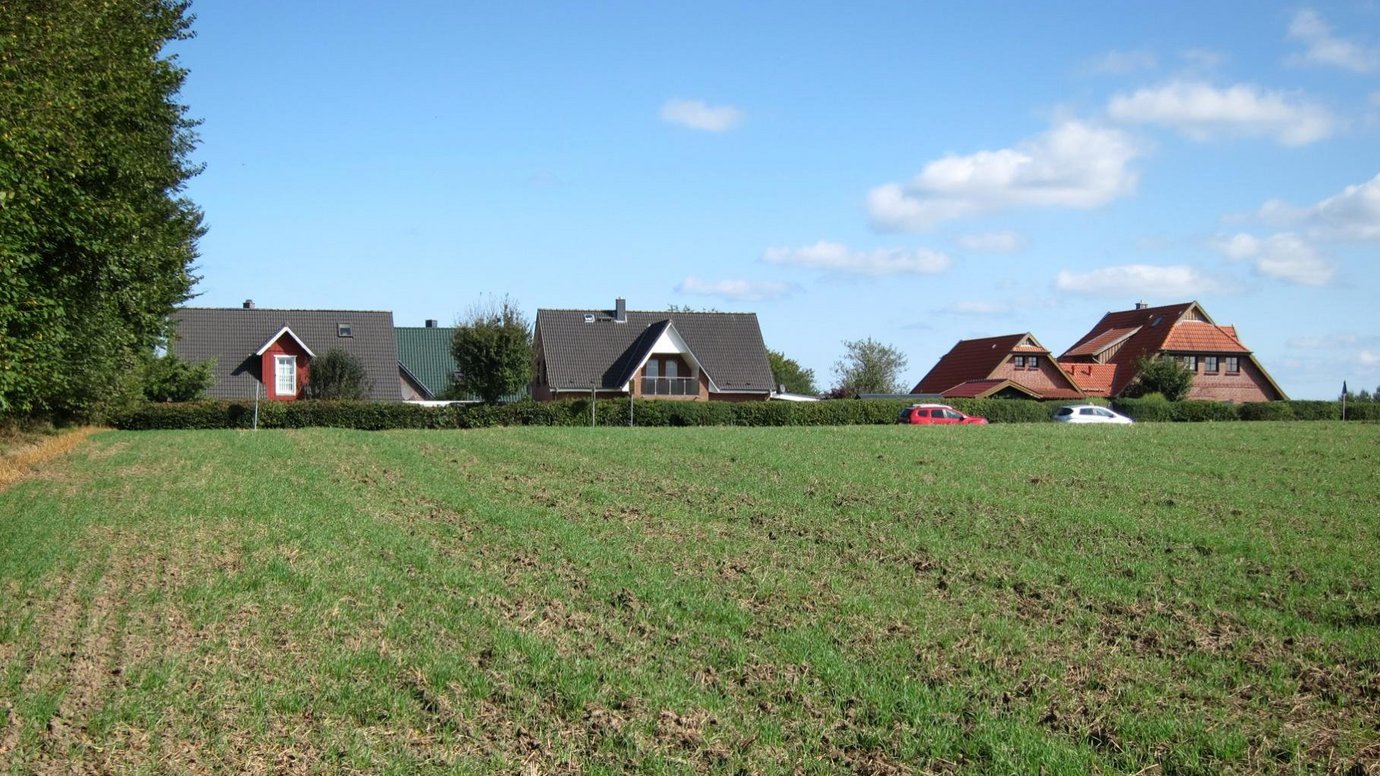 Feld mit Häusern im Hintergrund